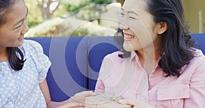 Daughter giving gift box to mother in garden 4k