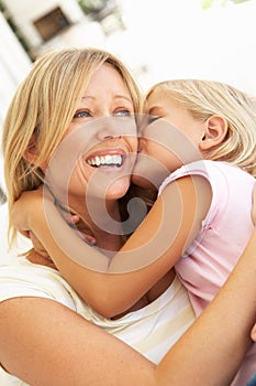 Daughter Giving Mother Kiss Relaxing On Sofa