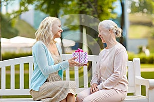 Daughter giving present to senior mother at park