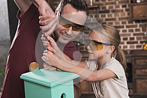 Daughter helping father make birdhouse in the