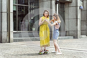 Daughter helping mum on skateboard