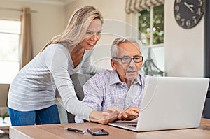 Daughter helping old father with laptop