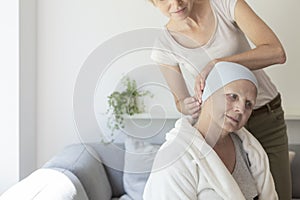 Daughter helping sick mother with headscarf