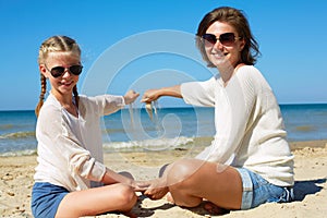 Daughter and her mom playing with sand on the beach.