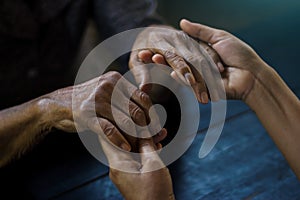 The daughter  holding hand and takes care mother elderly that is alzheimer and parkinson`s patient on dark background