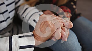 A daughter holding hands of her elderly mother. Care and support concept