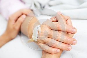 Daughter holding her mother hand in hospital