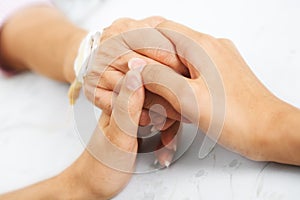 Daughter holding her mother hand in hospital