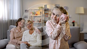 Daughter holding piggybank, mother and granny behind, teaching to save money