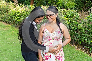 A daughter holds her mother`s hands on her pregnant belly
