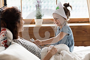 Daughter holds stethoscope imagines herself doctor listen mother heartbeat