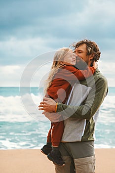 Daughter hugging father family lifestyle outdoor child with dad walking on the beach summer vacations