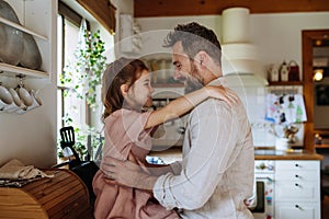 Daughter hugging father lovingly, sitting on kitchen counter. Unconditional paternal love, Father& x27;s Day concept.