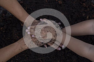 Daughter join hands with father dirty from the soil in planting trees in the garden. It is a family activity on holiday.