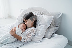 Daughter kid with infant sibling playing on bed wearing white