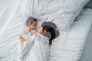 Daughter kid with infant sibling playing on bed wearing white