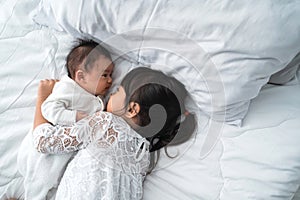 Daughter kid with infant sibling playing on bed wearing white