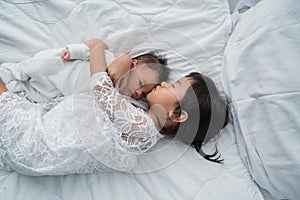 Daughter kid with infant sibling playing on bed wearing white