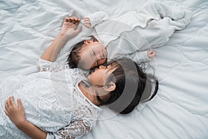 Daughter kid with infant sibling playing on bed wearing white