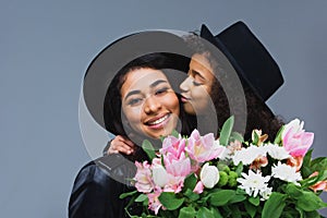 daughter kissing her mother while she holding bouquet