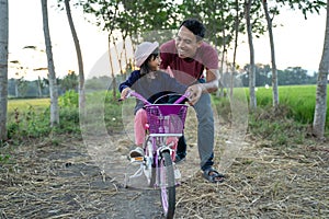 Daughter learning to ride bicycle with daddy