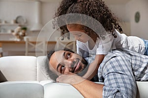 Daughter lying on daddy back enjoy time together at home