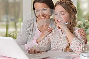 Daughter and mom use a laptop at home