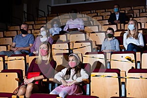 Daughter with mom wearing protective masks watching concert
