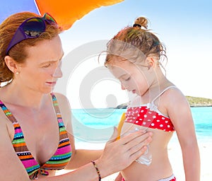 Daughter and mother in beach with sunscreen