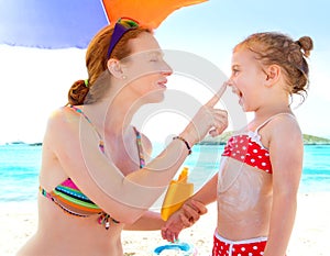 Daughter and mother in beach with sunscreen