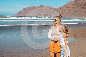 Daughter with mother with broken arm on beach. Arm cast, injured during family vacation in holiday resort. Concept of