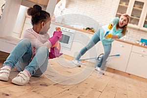 Daughter and mother diffusing cleaning spray on each other while cleaning