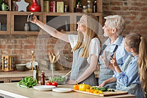 Daughter, mother and grandmother taking selfie while cooking together