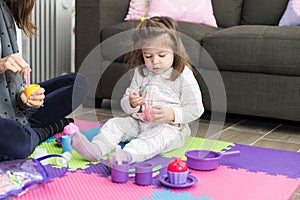 Daughter And Mother Playing Tea Party At Home