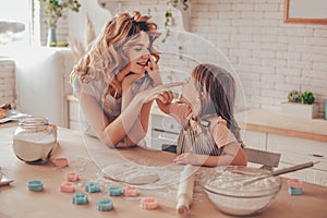 Daughter and mother spending time together on the hone kichen and putting flour on the noses each other