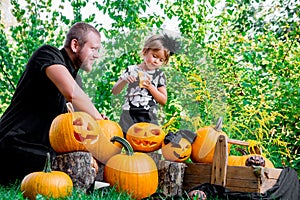 Daughter near father who pulls seeds and fibrous material from a pumpkin before carving for Halloween. Prepares jack-o-lantern. D