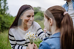 Daughter picking flowers, giving them to mother. Concept of family ecological hobby in nature. Mother& x27;s Day.