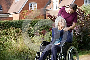 Daughter Pushing Senior Mother In Wheelchair