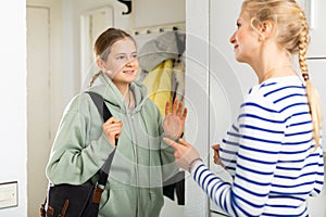 Daughter saying goodbye mom in entrance hall of apartment