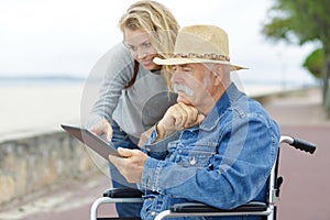 Daughter with senior man in wheelchair in park