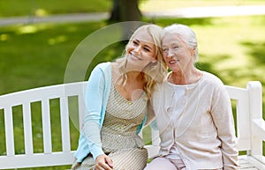 Daughter with senior mother hugging on park bench