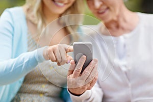 Daughter and senior mother with smartphone at park