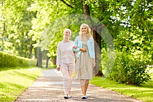 Daughter with senior mother walking at summer park