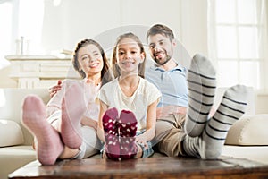 Daughter sitting with hugging parents on sofa at home