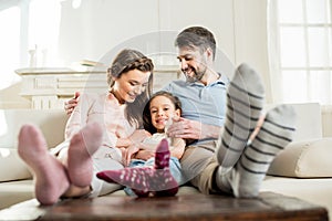 Daughter sitting with parents on sofa at home