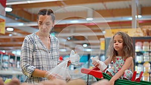 Daughter sitting in supermarket trolley. Lovely family, mother and little daughter buying fruit and vegetables in