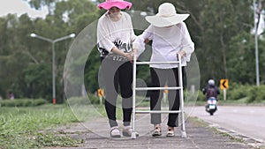 Daughter take care elderly woman walking on street.