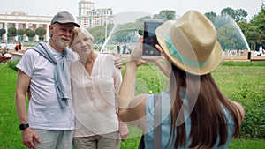 Daughter taking photo on mobile phone of her senior parents on vacation trip in Gorky Park in Moscow