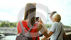 Daughter taking photo of senior parents on vacation trip in Paris. near Eiffel Tower and river Seine