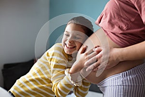 Daughter touching the belly of her pregnant mother